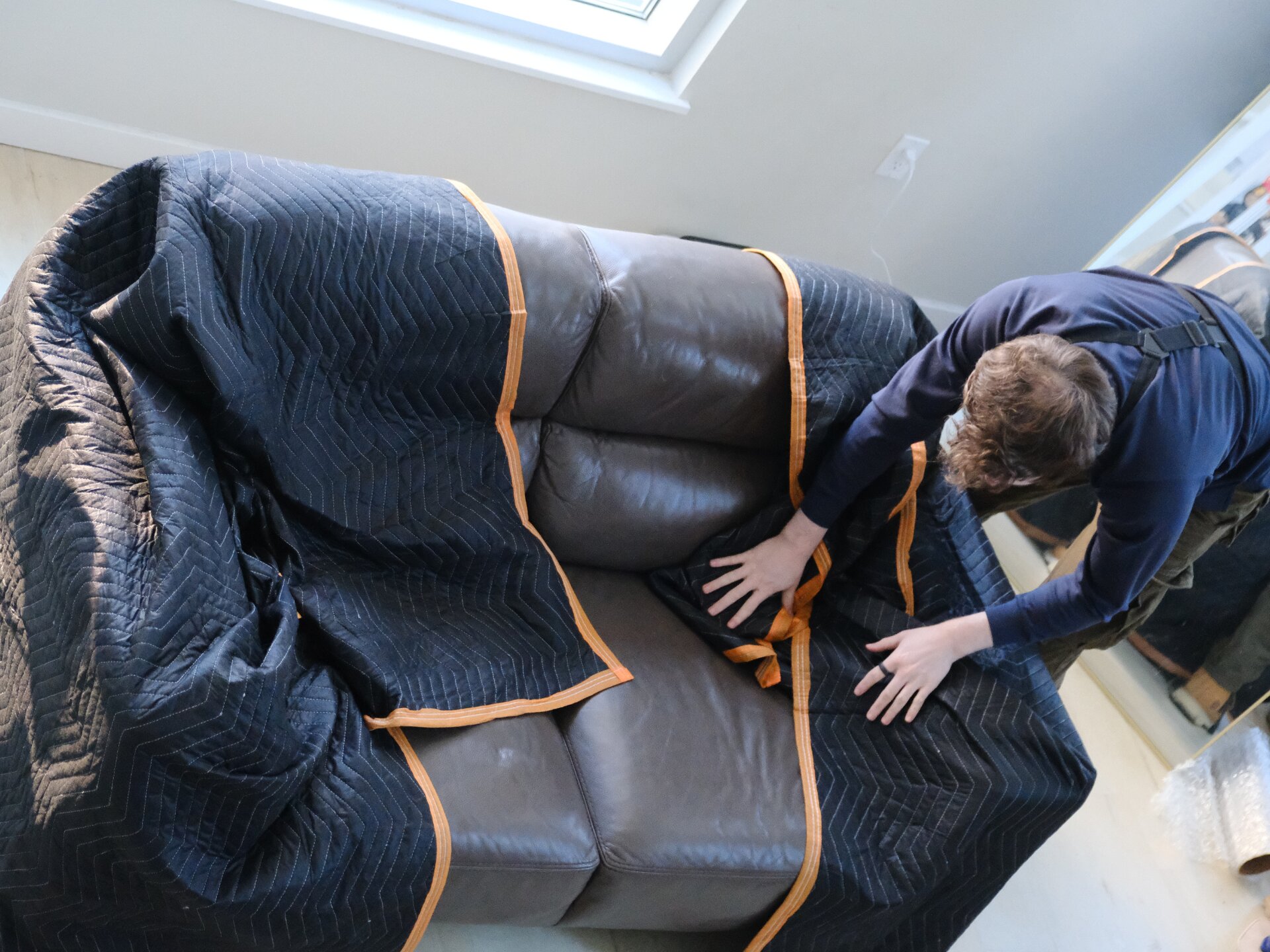 Crew wrapping couch under skylight in SF apartment